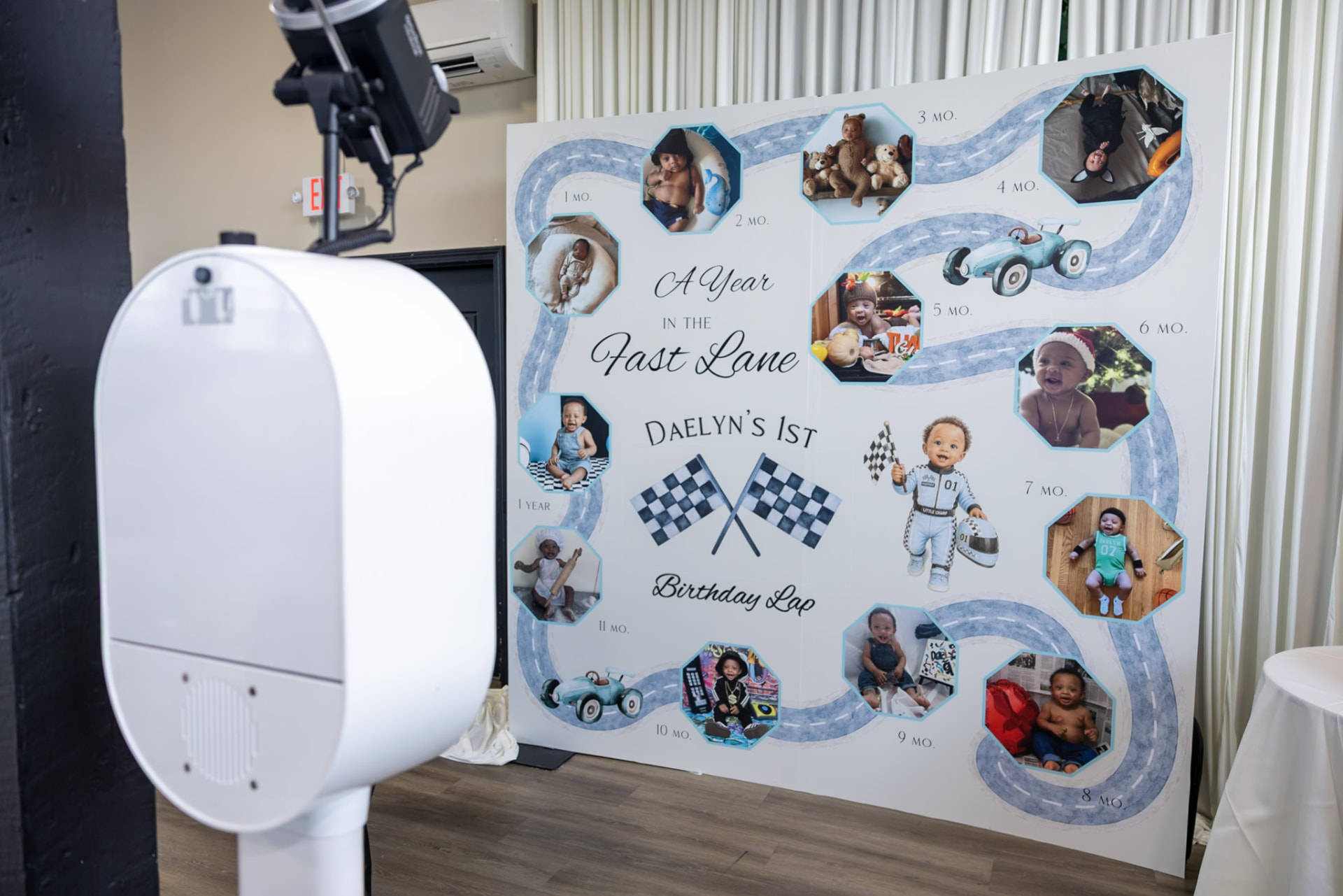 Photo booth beside a milestone photo board at a first birthday party