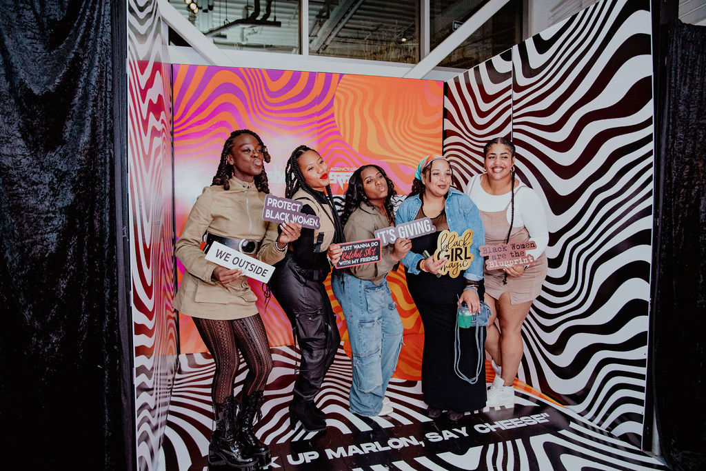 Five guests posing with props in a zebra-print photo booth